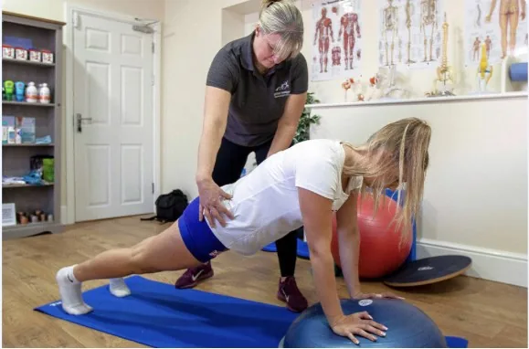 Therapist guiding a client through a core exercise over a stability ball